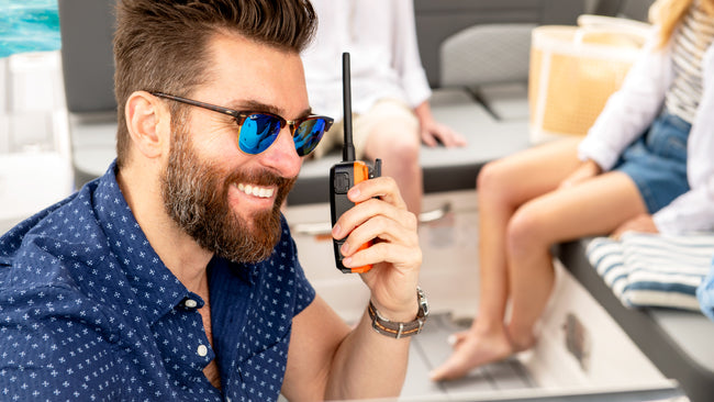 Man wearing sunglasses holding a marine radio on a boat