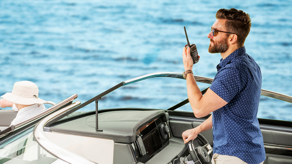 Man on a boat using a walkie-talkie with a water in the background