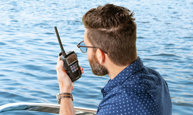 Man on a boat using a Blue Bound 150 marine radio with water in the background