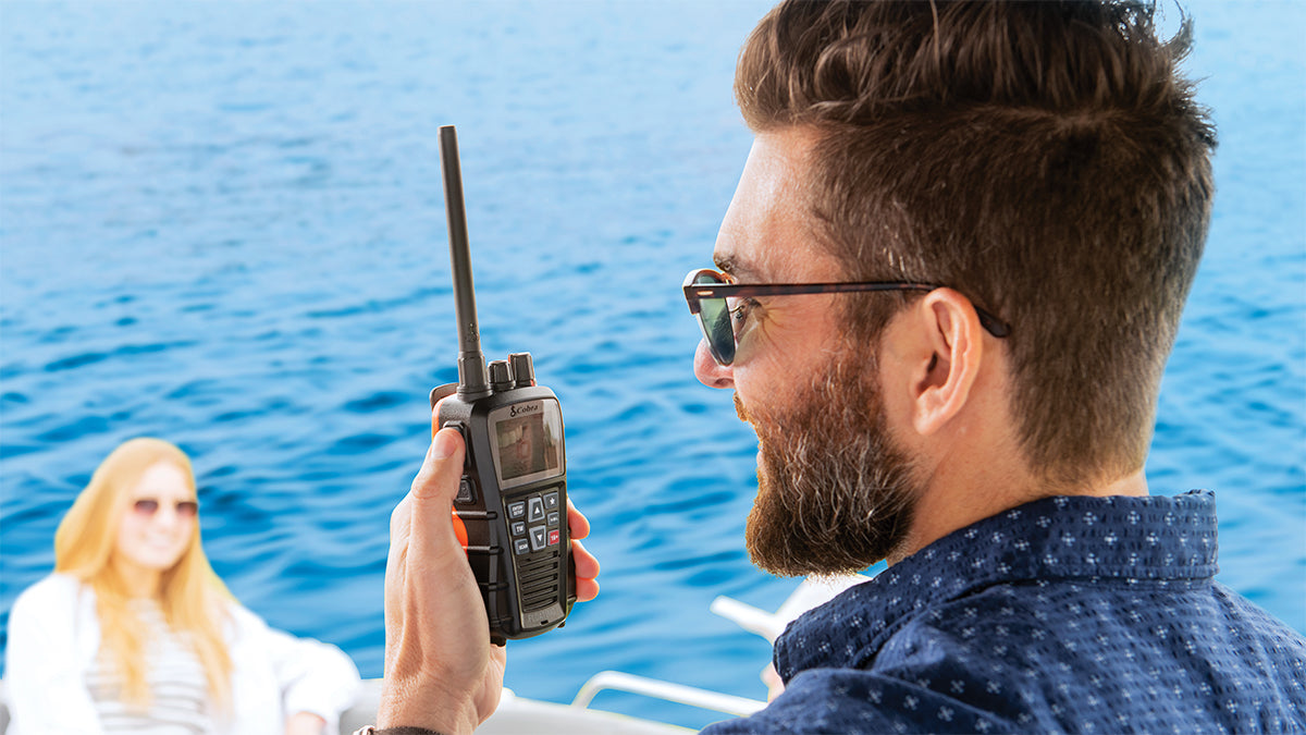 Man on a boat using a marine radio with a woman in the background
