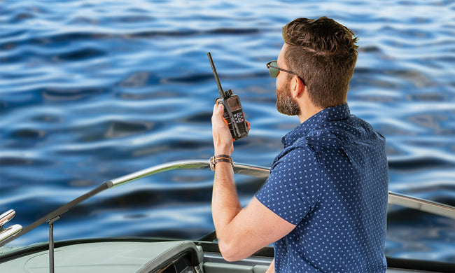 Man on a boat using a marine radio with water in the background