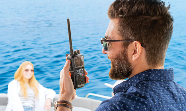 Man on a boat using a marine radio with a woman in the background